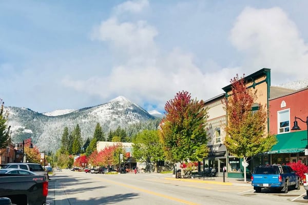 Wooden welcome sign at entrance to forest cabin community with mountain view and autumn foliage